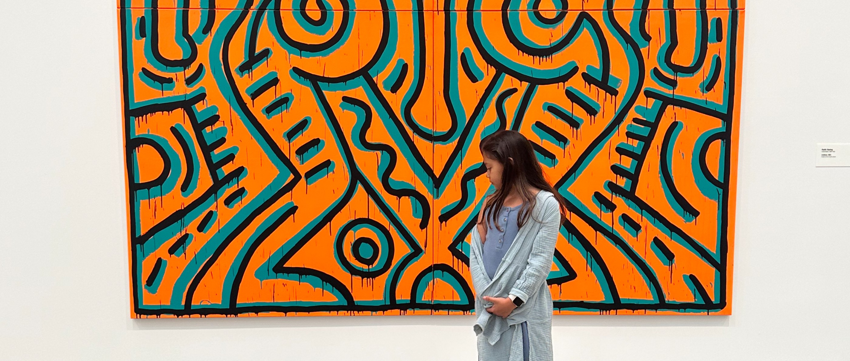 A child standing before a large orange and teal painting in a museum gallery