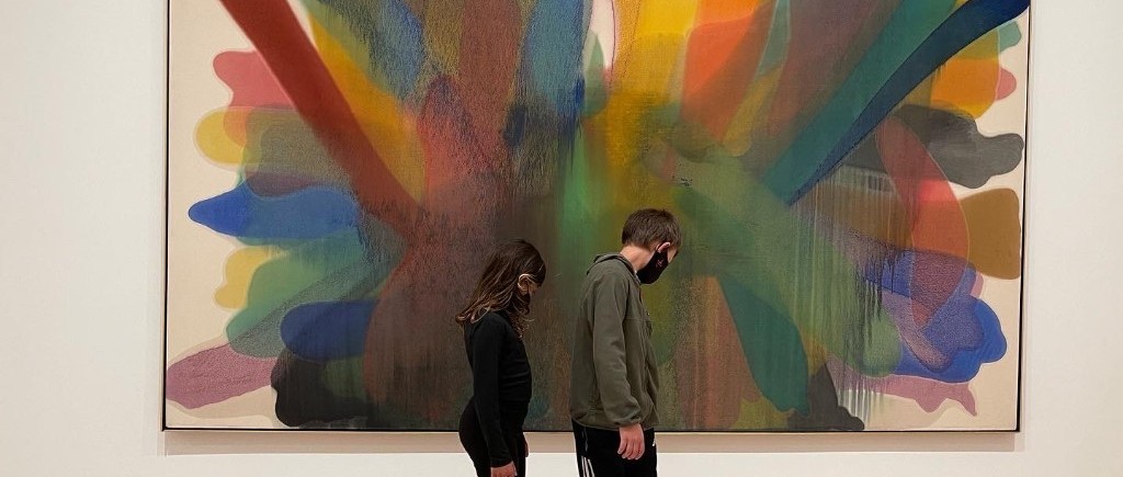Two children before a colorful abstract expressionist painting