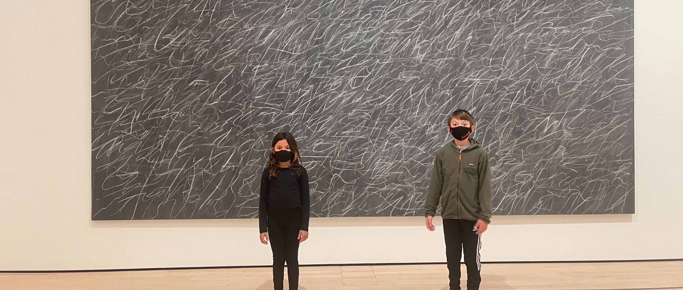 Two children in front of a gestural black-and-white canvas
