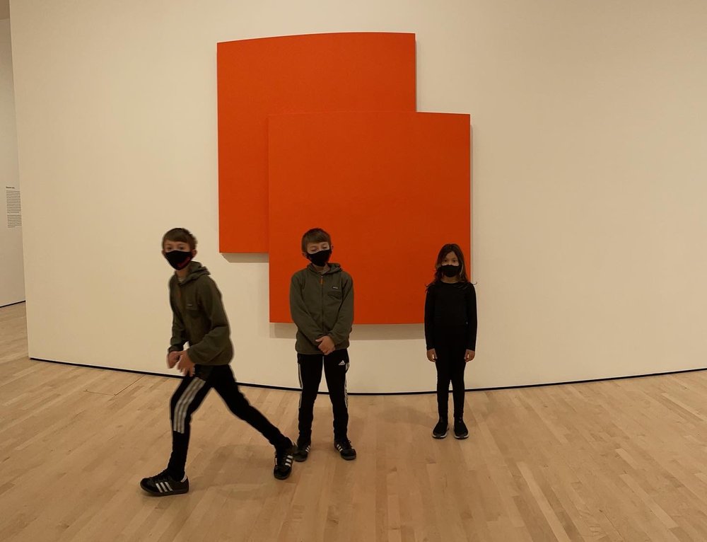Three children standing before a large orange painting in a gallery