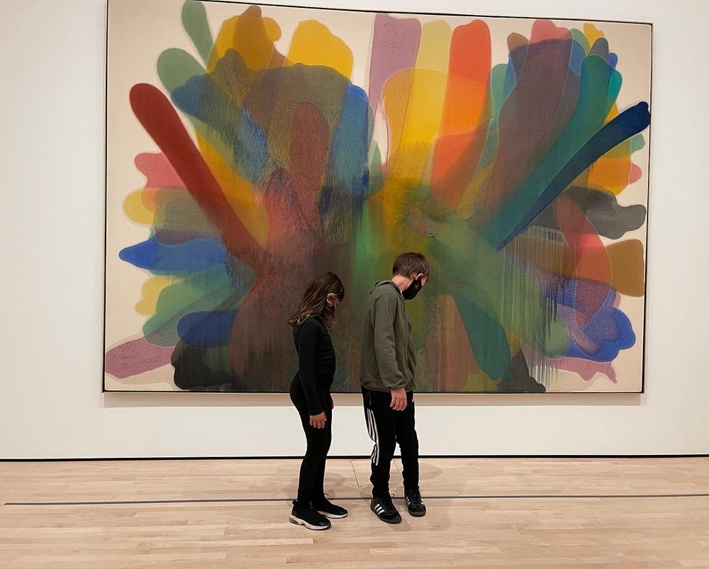 Two children looking at a large colorful abstract painting in a gallery